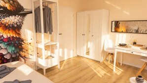 A bedroom with a bed, a wardrobe, a desk, and a chair.