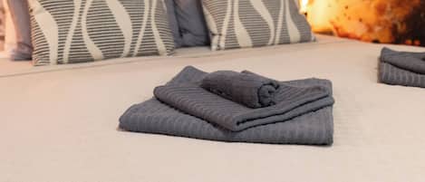 A neatly made bed with folded towels and striped pillows.