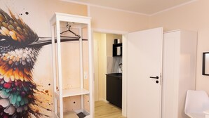 A room with a white wardrobe, a white chair, and a colorful wall mural.