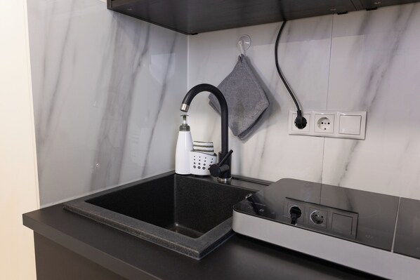 A kitchen with a black countertop, a built-in stove, and a modern faucet.