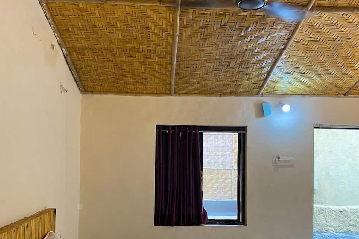 Una habitación con cama, ventana con cortinas, ventilador de techo y vista al exterior.