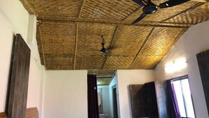 Quarto com teto de tecido, cama, janela com cortinas e ventilador de teto.