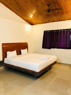 A single bed with a wooden headboard in a room with a wooden ceiling and a window with purple curtains. - The Paradise Retreat (Akola)