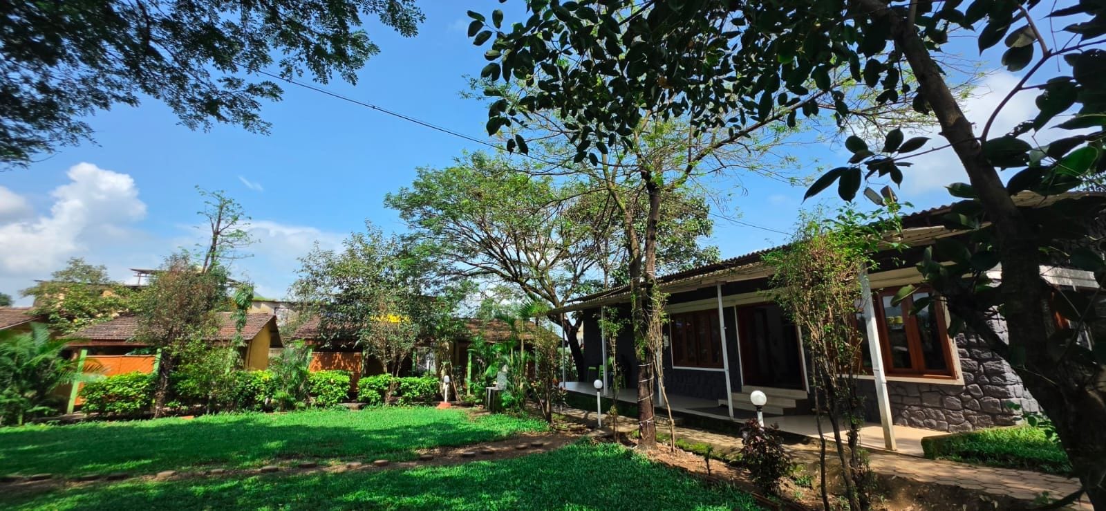 Una propiedad residencial con un jardín bien cuidado, un espacio de estar cubierto al aire libre y un edificio de piedra.