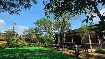 Una propiedad residencial con un jardín bien cuidado, un espacio de estar cubierto al aire libre y un edificio de piedra.