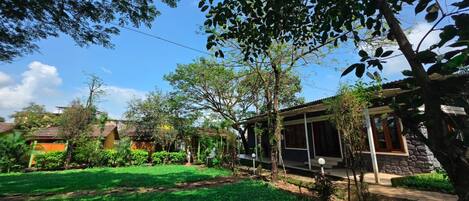Una propiedad residencial con un jardín bien cuidado, un espacio de estar cubierto al aire libre y un edificio de piedra.