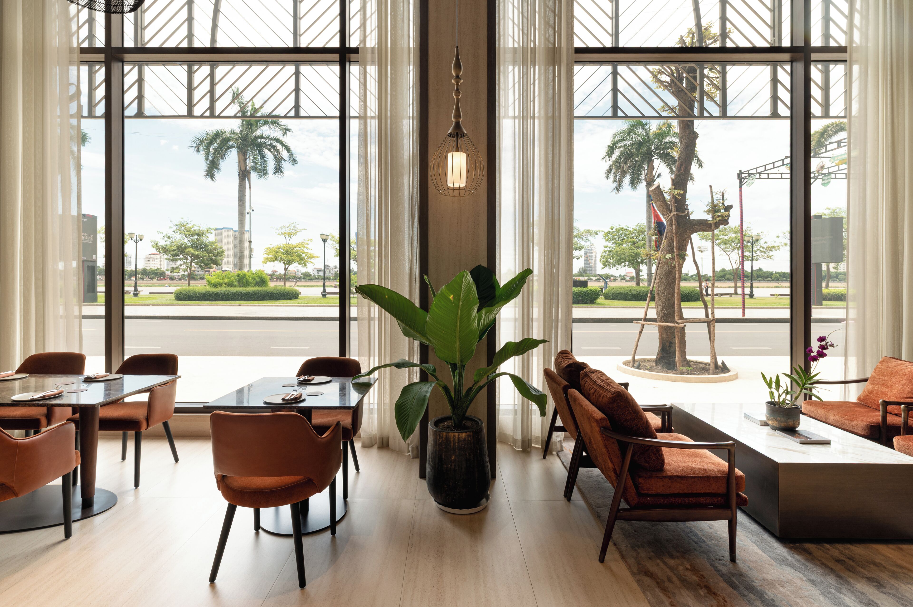 Un moderno vestíbulo de hotel con ventanas amplias, una planta central y zonas de estar.