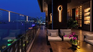 Un área de descanso moderna con vistas a la ciudad, asientos y un bar con estanterías.