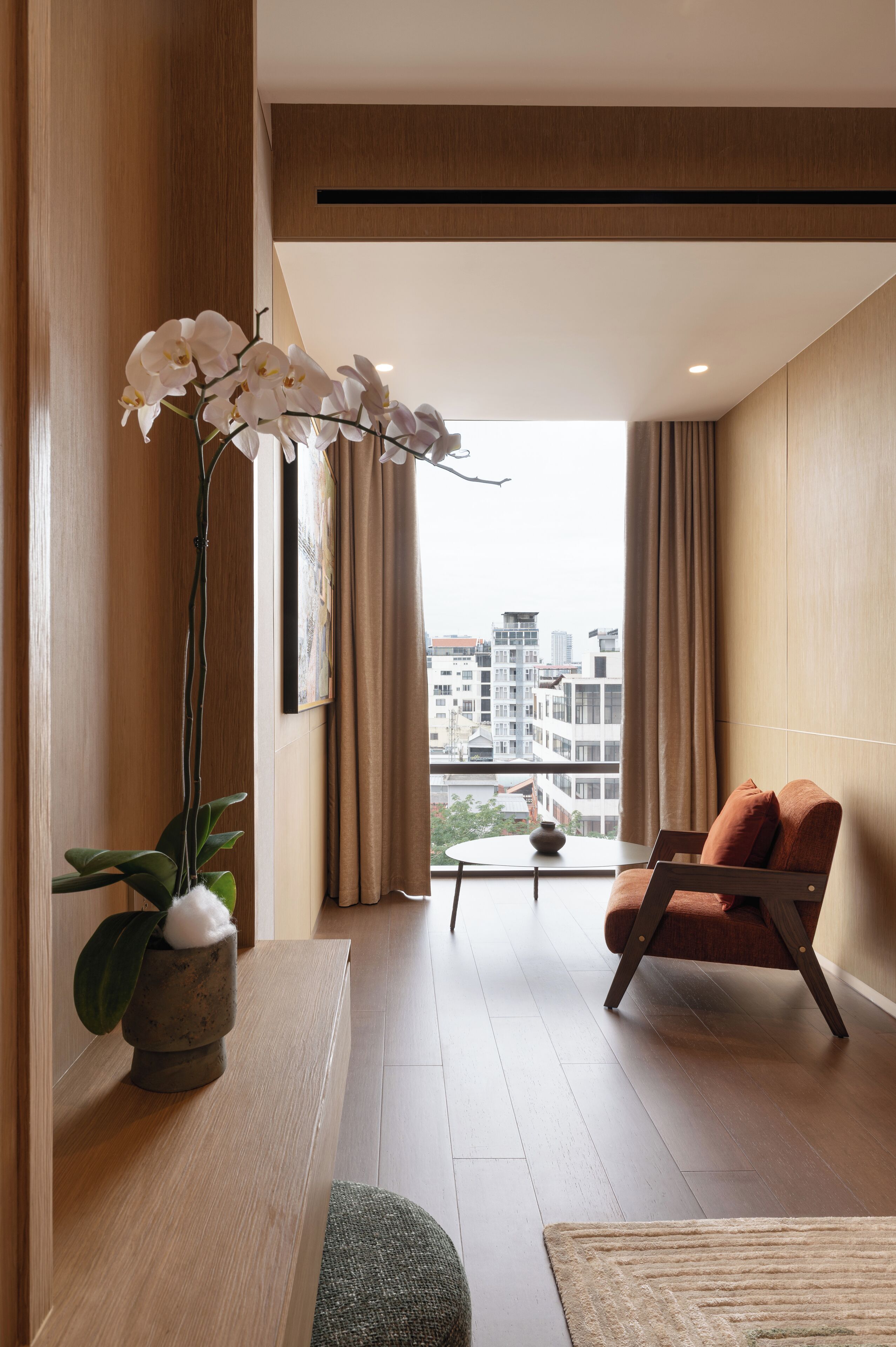 A modern living room with a large window, a potted plant, a sofa, and a small table.