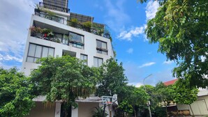 A modern multi-story building with balconies, surrounded by lush greenery and a clear sky. - Charming bed & breakfast in delightful Hà Nội with AC, WiFi (Hà Nội)