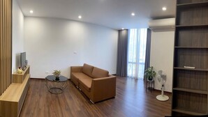 A modern living room with a sofa, a coffee table, a TV, and a bookshelf. - Charming bed & breakfast in delightful Hà Nội with AC, WiFi (Hà Nội)