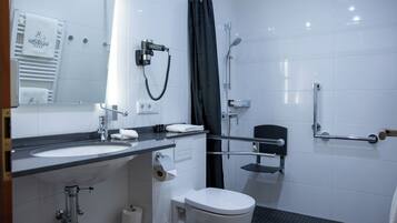 Un baño moderno con lavamanos, inodoro y zona de ducha blancos.