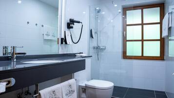 A modern bathroom with a large mirror, a black countertop, a white toilet, and a glass-enclosed shower area.