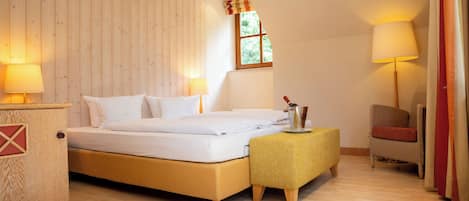 Un dormitorio ordenado con cama, lámparas de noche, una mesita y una silla.