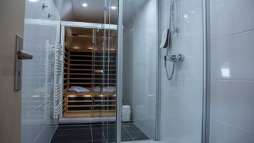 A modern bathroom with a glass-enclosed shower, a built-in bench with storage, and a white tiled floor.