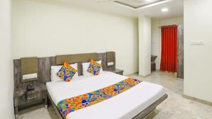A hotel room with a bed, nightstands, a ceiling fan, and a red curtain. - Hotel Krishna  (Nagpur)