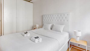 Een hotelkamer met een groot bed, een nachtkastje met een lamp en een kledingkast.