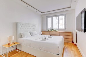 Une chambre à coucher moderne avec un grand lit, une table de chevet, une commode et une fenêtre donnant sur un beau paysage.
