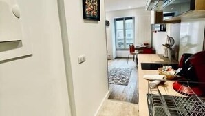 A modern kitchen with a dining area, a large window, and a tiled floor. - Ben Nevis charming studio in the heart of the lively life of the Pré Carré (Annecy)