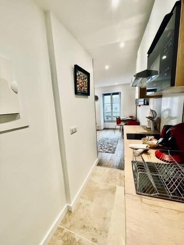 Una cocina moderna con zona de comedor, un amplio ventanal y suelo de baldosas.