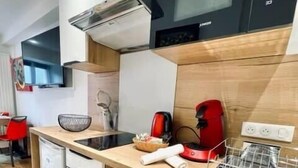 A compact kitchen with a built-in washing machine, a microwave, and a coffee maker. - Ben Nevis charming studio in the heart of the lively life of the Pré Carré (Annecy)