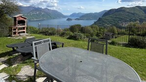 An outdoor seating area with a metal table and chairs, overlooking a lake and mountains. - TOBIA HOUSE Beautiful Lake View (San Rocco)