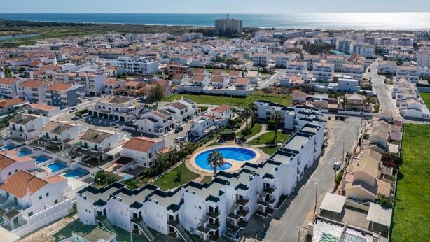 A coastal residential area with white buildings, a central swimming pool, and a view of the sea. - Sun Lovers Altura T1 Pool & Balcony (Altura)