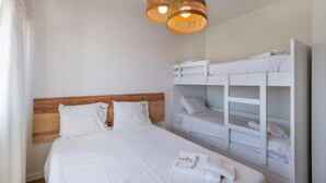 A bedroom with a wooden headboard bed, two bunk beds, and a hanging light fixture. - Sun Lovers Altura T1 Pool & Balcony (Altura)