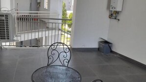 A balcony with a metal chair and a small table, a white railing, and a view of the outside. - Jolly house 1 (Cosenza)
