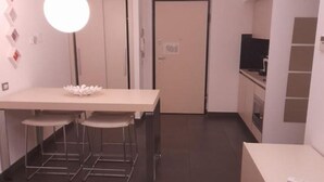 A compact kitchen with a dining area, a single light fixture, and a closed door. - Jolly house 1 (Cosenza)