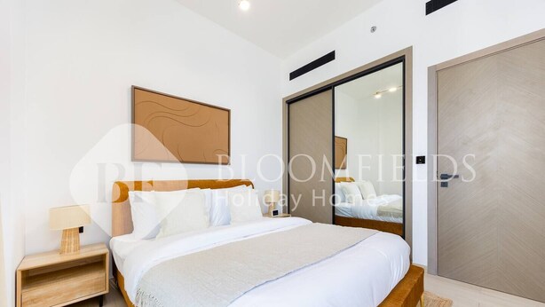 A modern bedroom with a large bed, a nightstand, a mirror, and a sliding door. - Bloomfields Cozy 1BR Binghatti Nova  (Dubai)