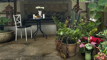 A patio area with a stone fireplace, a white chair, and various potted plants.