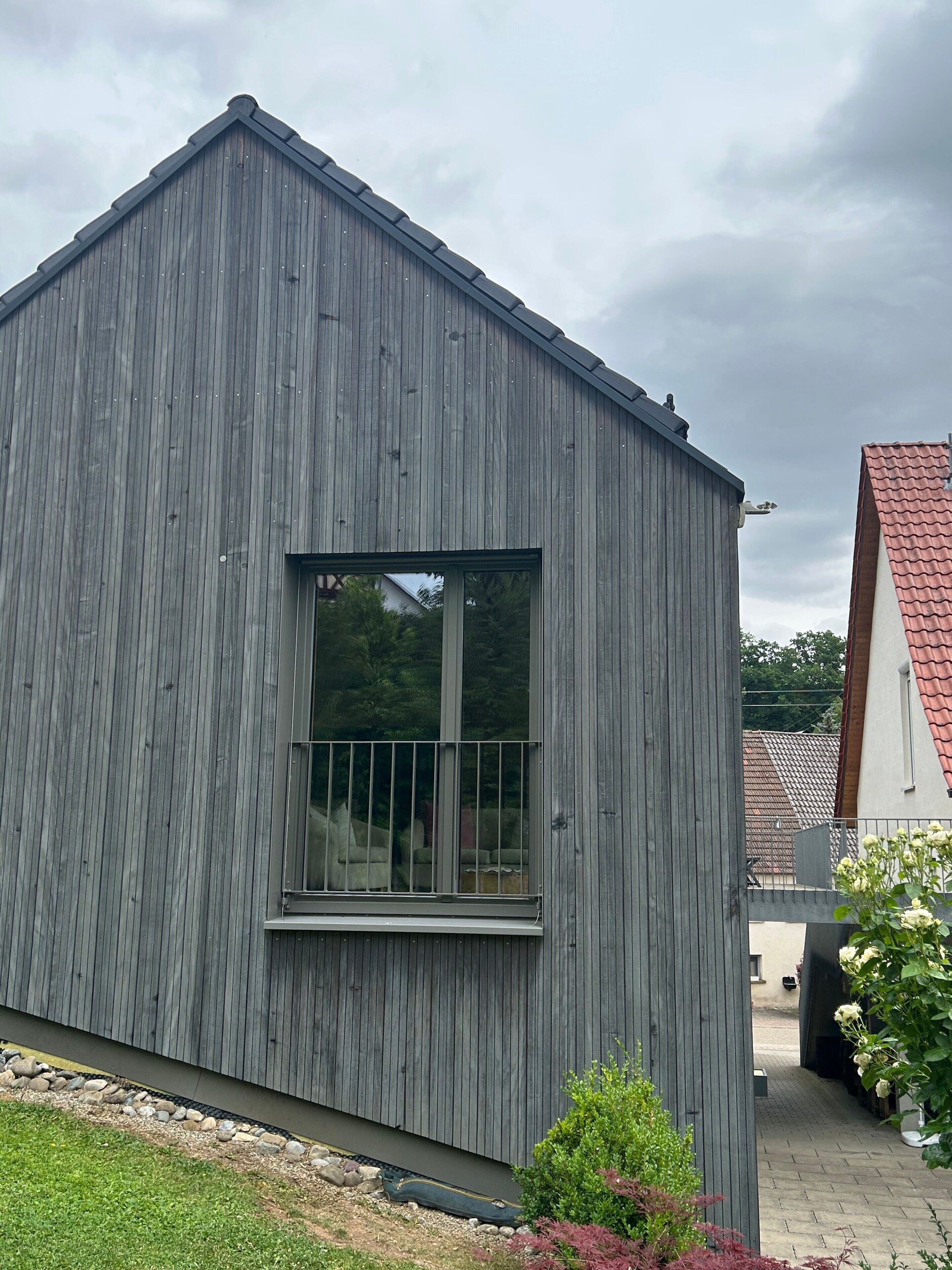 Un edificio de madera gris con una ventana y un portón de metal.
