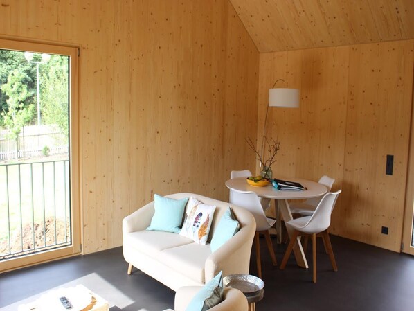 A room with a sofa, chairs, a table, and a lamp.
