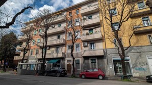 Ein mehrstöckiges Wohngebäude mit Balkonen, einer grünen Markise und geparkten Autos.