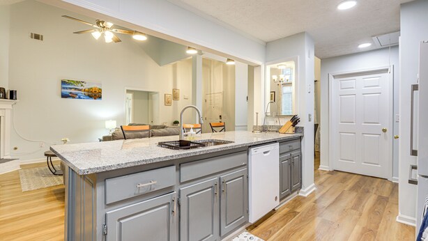 A spacious kitchen with a large island, grey cabinets, and a dishwasher.