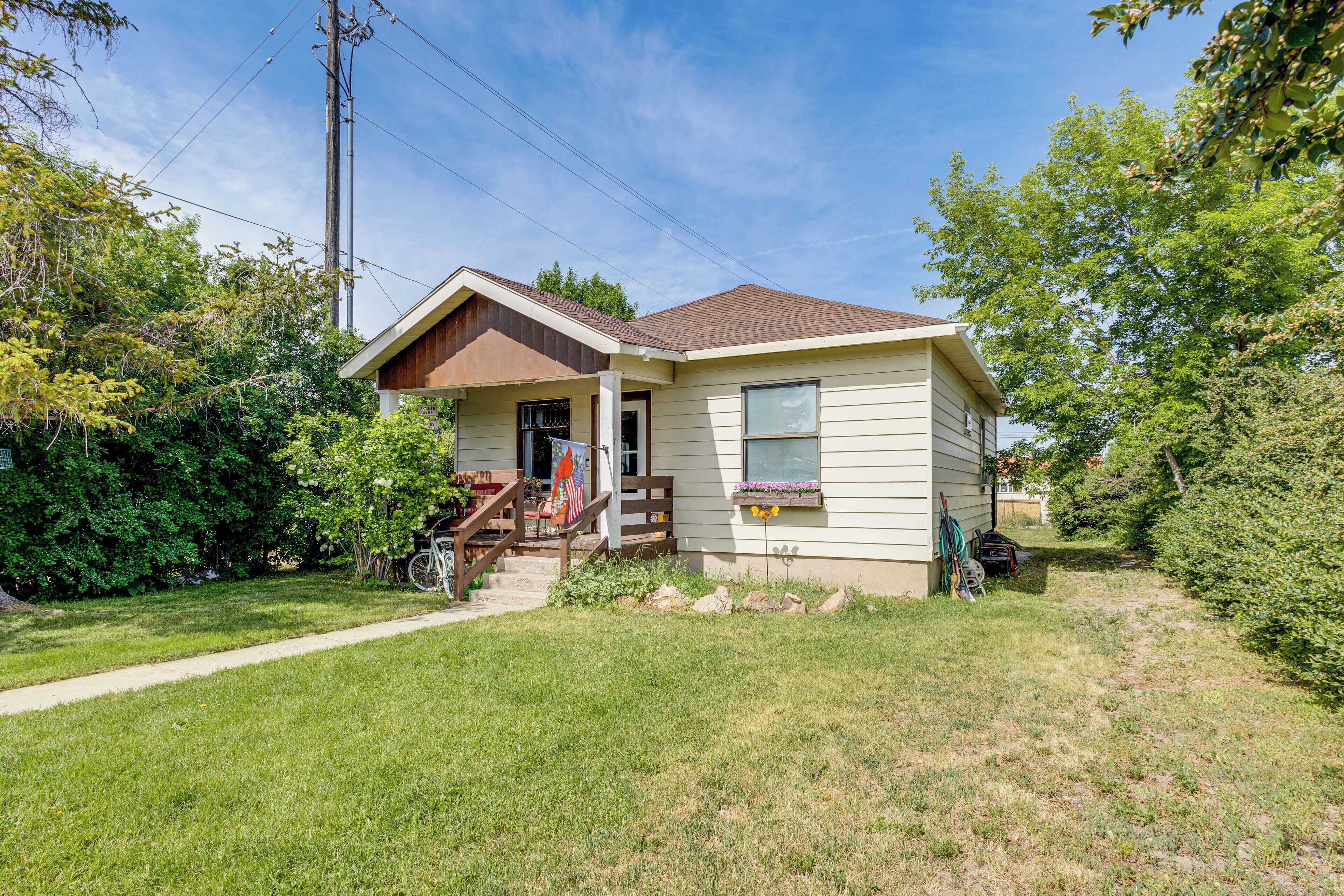 A single-story house with a front porch, a small garden, and a flag.