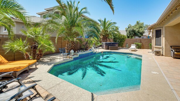 A swimming pool surrounded by palm trees and lounge chairs.