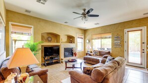 A living room with a sofa, a glass coffee table, a television, and a fireplace.
