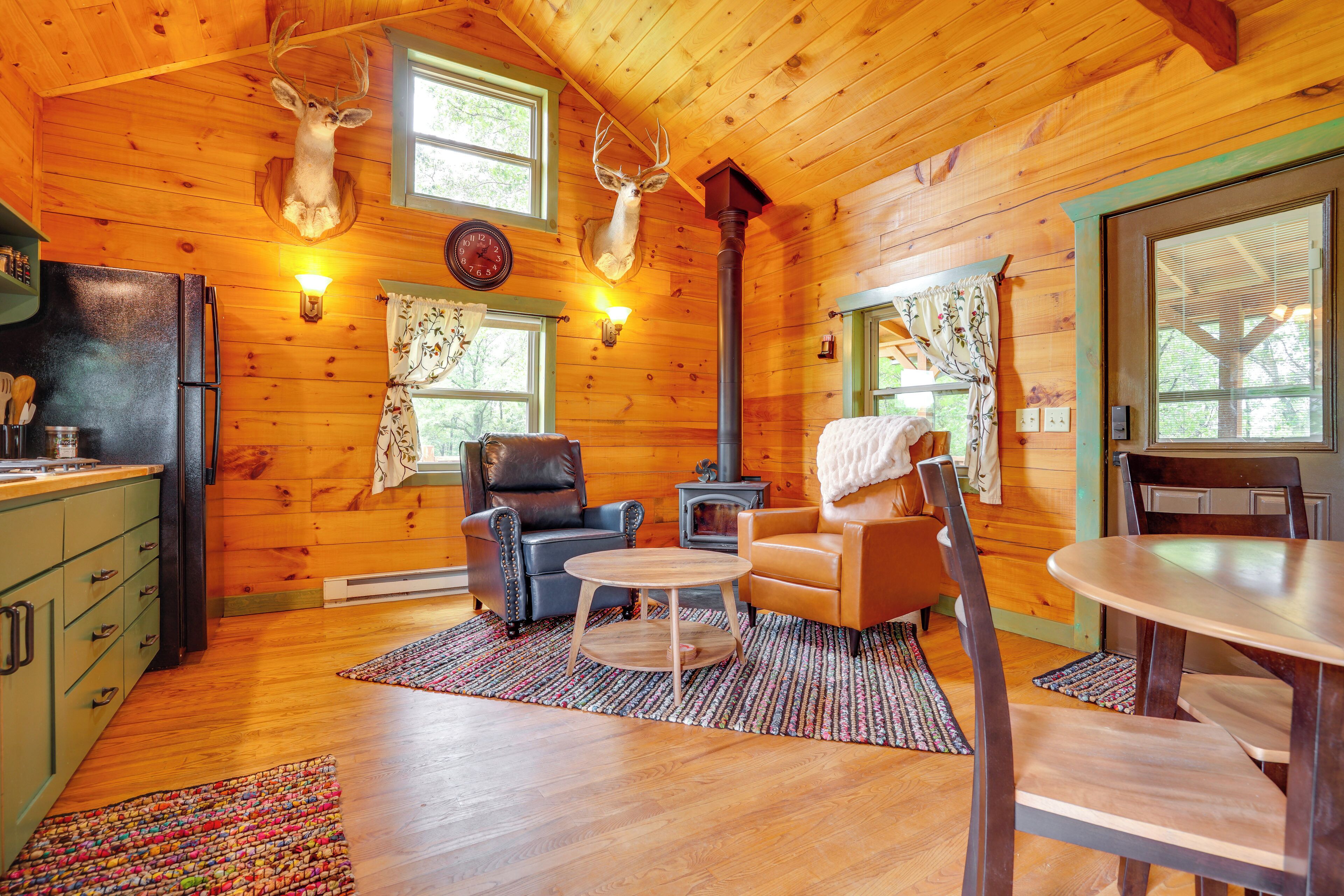 Un intérieur de chalet chaleureux avec des murs en bois, une cheminée, une table à manger et un coin cuisine.