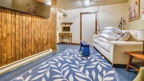 A living room with a wooden wall, a sofa, a coffee table, and a patterned rug.