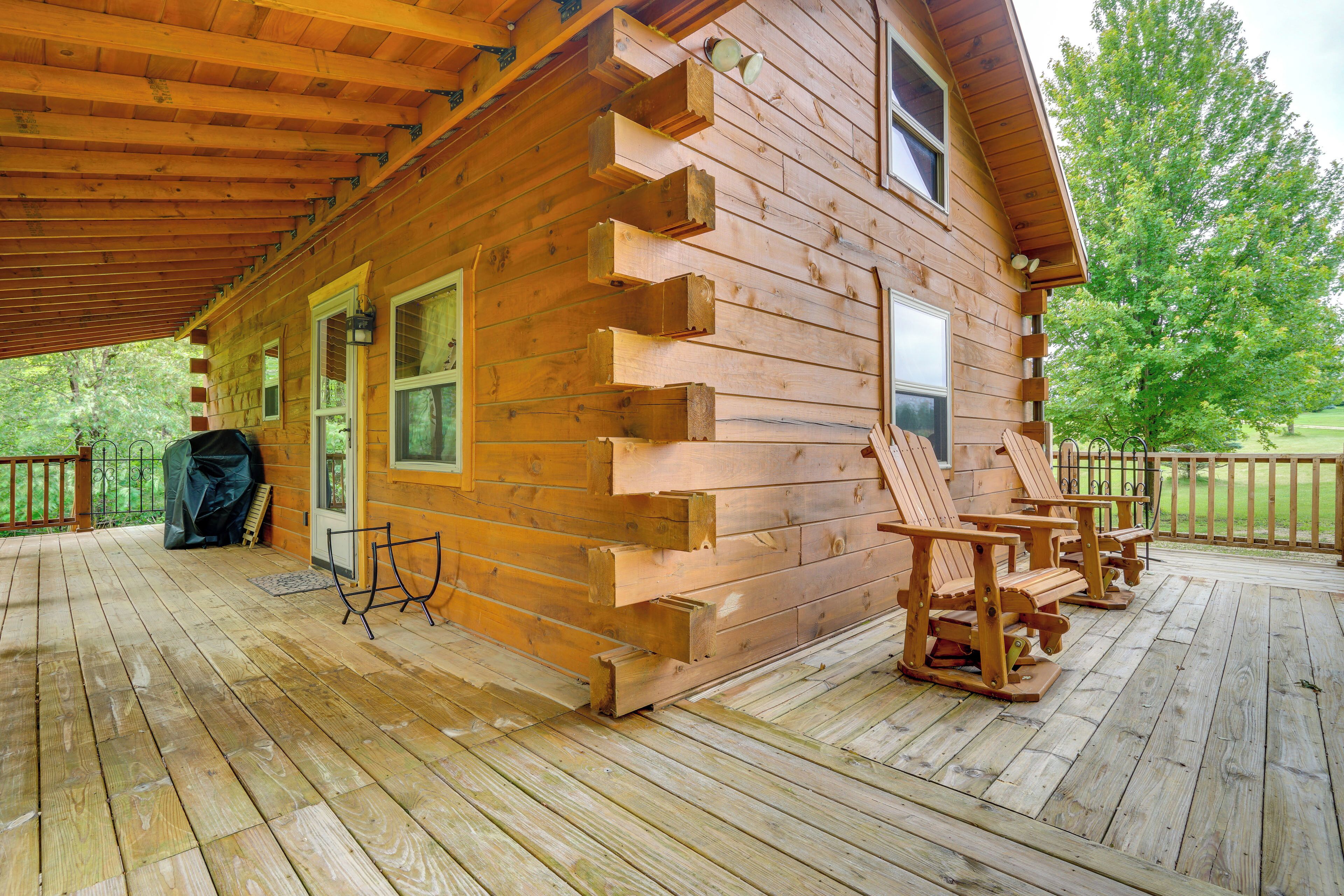 A wooden cabin with a porch, two rocking chairs, and a covered area.