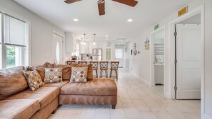 A spacious living room with a large brown sectional sofa, a ceiling fan, and a kitchen area in the background. - Family Retreat in Old Lyme Gated Miami Beach (Old Lyme)