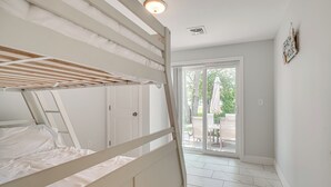 A bedroom with a bunk bed, a sliding glass door leading to a patio, and a sign on the wall. - Family Retreat in Old Lyme Gated Miami Beach (Old Lyme)