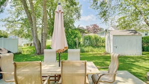 An outdoor patio with a table and chairs, surrounded by trees and a white shed. - Family Retreat in Old Lyme Gated Miami Beach (Old Lyme)