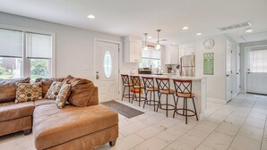 A modern kitchen with white cabinets, a central island with bar stools, and a dining area. - Family Retreat in Old Lyme Gated Miami Beach (Old Lyme)