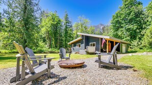 A cabin with a deck, outdoor seating, and a fire pit.