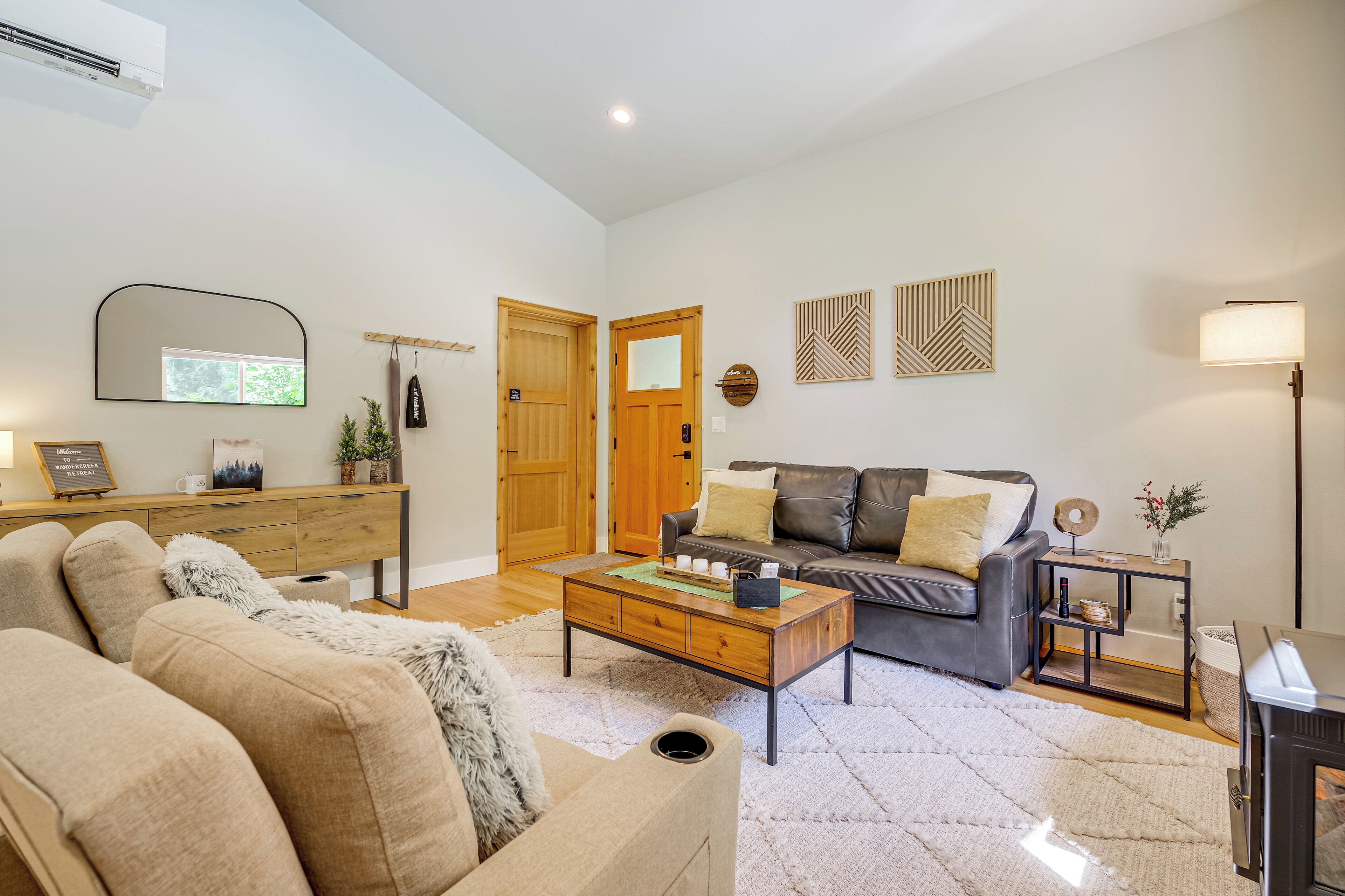 A living room with a sofa, coffee table, and a fireplace. There is a wooden door and a mirror on the wall.