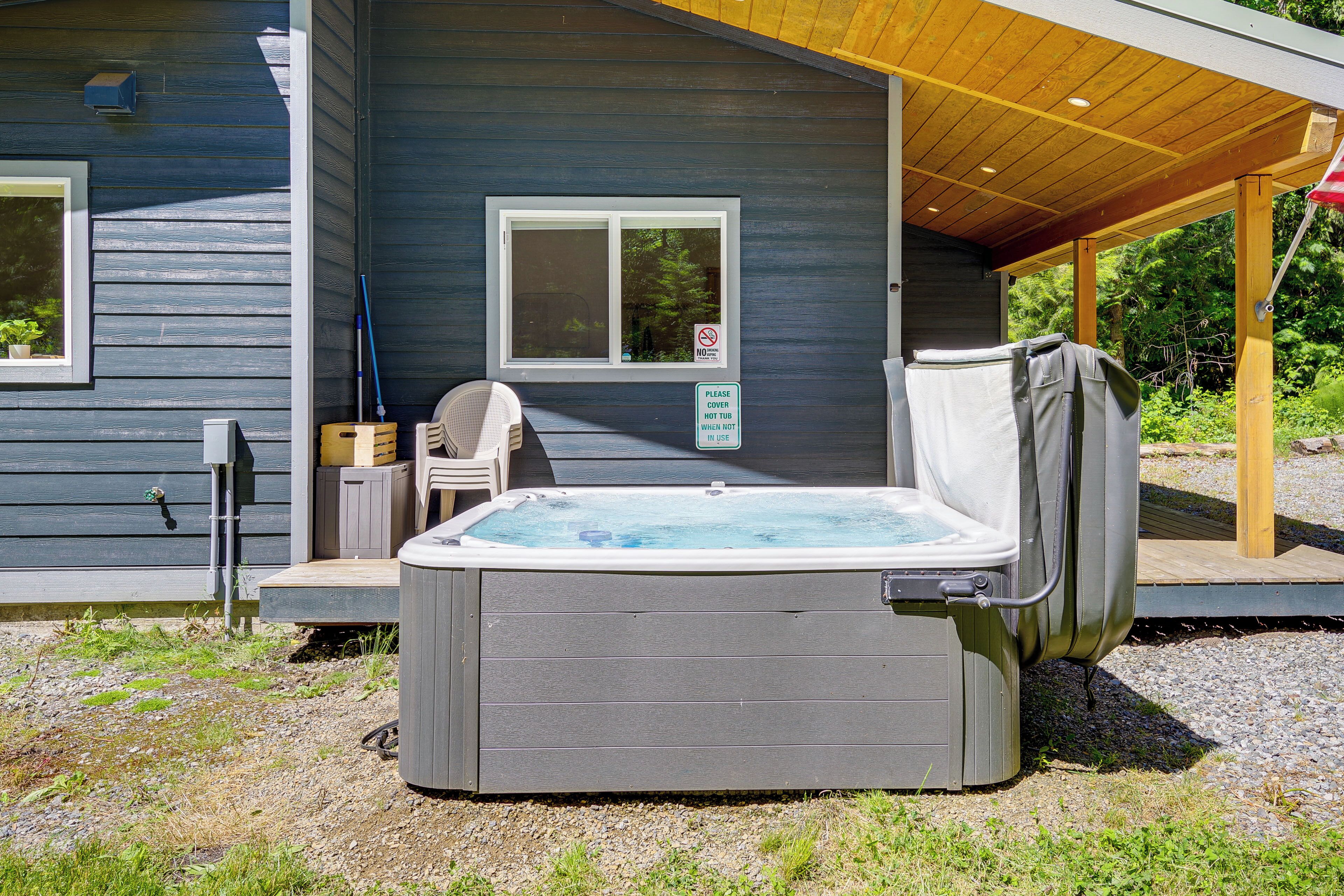 Un jacuzzi en el exterior de una casa con un porche cubierto, una ventana y un letrero que indica el uso del jacuzzi.