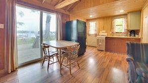 Un interior de madera con una mesa de comedor, sillas, un refrigerador, una zona de cocina y un sofá.